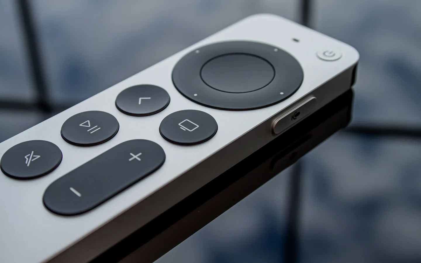 A escolha de um serviço se resume a critérios verificáveis, não a promessas. Close de um controle remoto branco e prata com touchpad circular e botões escuros